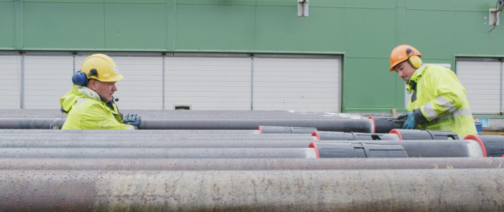 Two workers in the oil and gas sector removing the BEWI Universal Protector from a pipe